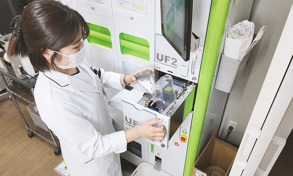 アイケイ薬局 全自動錠剤分包機 Xana-UFのユニバーサルフィーダーに薬剤を投入する様子